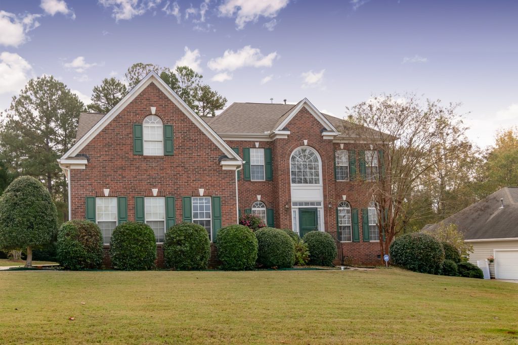A brick residential home with southern architecture surrounded by autumn foliage, listed for sale.