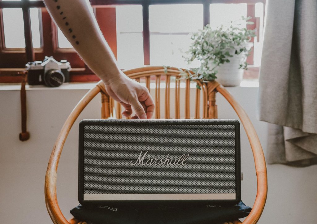 A Marshall Stanmore bluetooth speaker sits on a surface indoors, with a chair and camera equipment visible nearby.