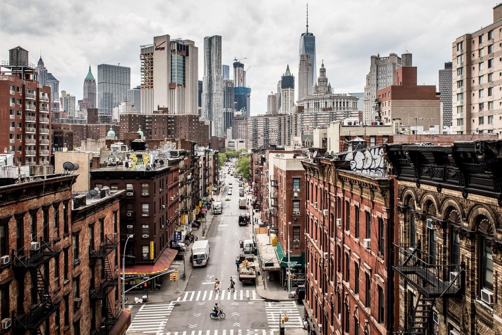Manhattan street scene in New York City's Chinatown, with traffic, older buildings, and modern skyscrapers creating a contrast of old and new architecture.