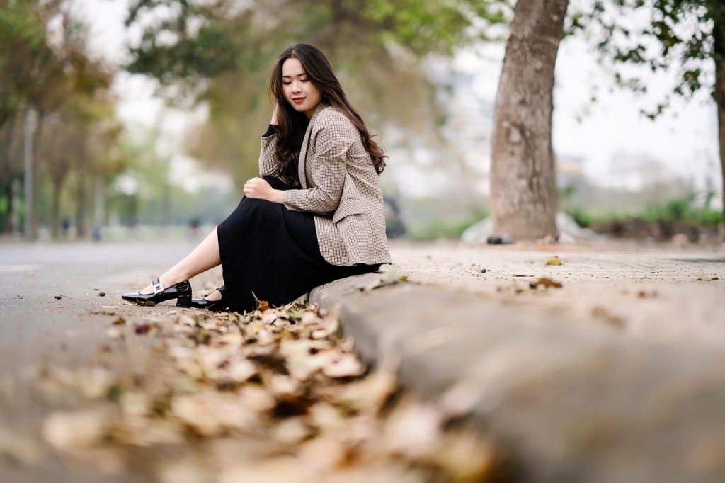 A person sitting outdoors on a road, posing for a portrait.