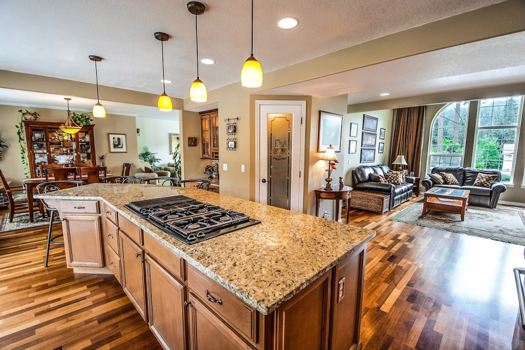 A home interior showing a kitchen with countertops and an adjoining living room area.