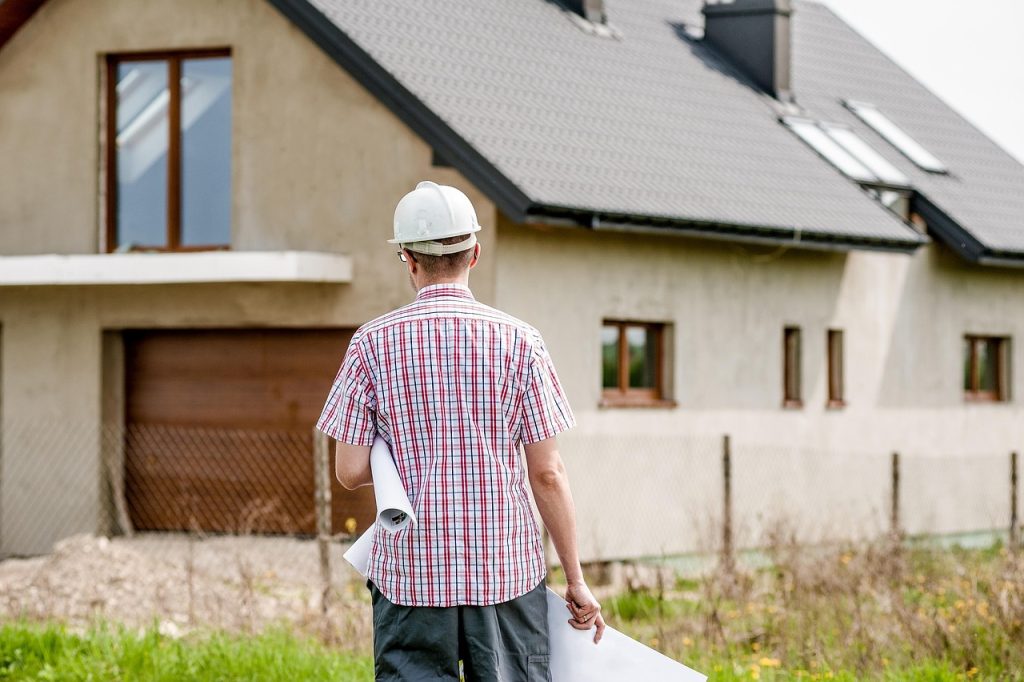 A person in a professional role reviews building plans, with documents and construction-related materials nearby.